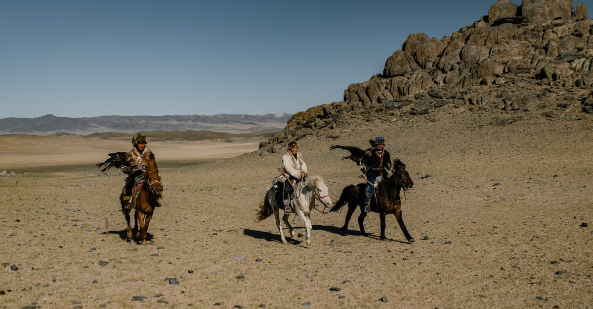 Unknown quest area in desert - Ethnic people on horses near rocky formation