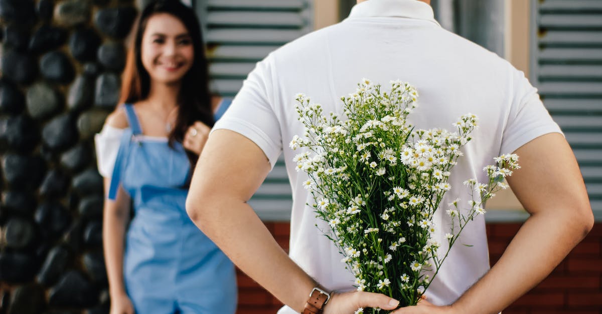 Unlock Surprise Mode? - Man Holding Baby's-breath Flower in Front of Woman Standing Near Marble Wall