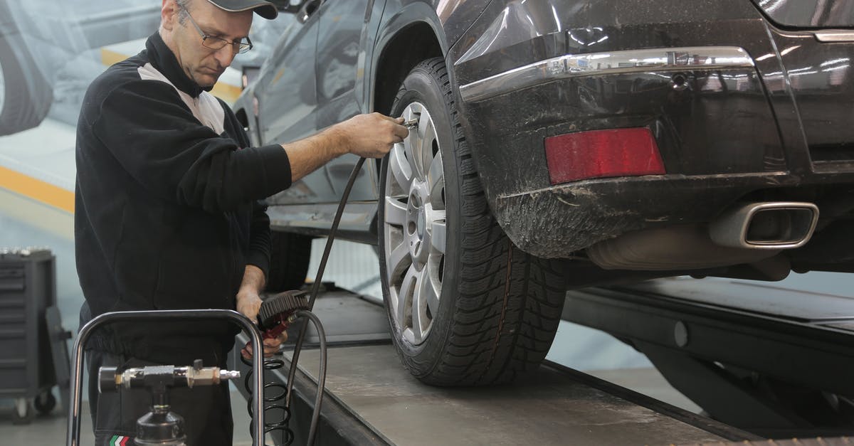 Unmatched Air Traffic Control (UATC) Voice Recognition Option not visible - Serious car mechanic pumping up car wheel in modern service garage