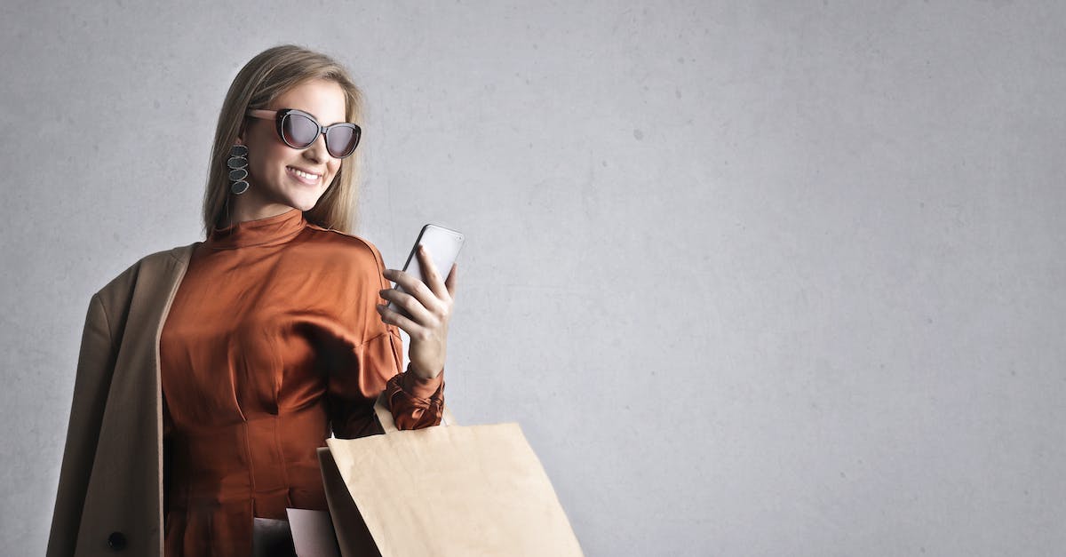 Using DirectX 11, getting message: Shader model 3.0 or better graphic device required - Smiling female in trendy wear and stylish sunglasses standing with paper shopping bags on background of gray wall and browsing mobile phone