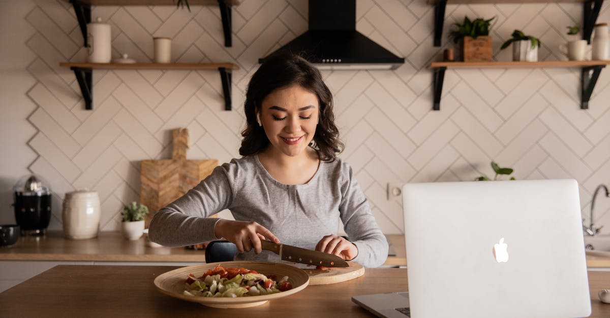 Using Enchantment nbt tag in json recipe - Cheerful ethnic female cutting fresh vegetables on cutting board while sitting at wooden table in kitchen with open portable computer in apartment Using Enchantment nbt tag in json recipe - Cheerful ethnic female cutting fresh vegetables on cutting board while sitting at wooden table in kitchen with open portable computer in apartment