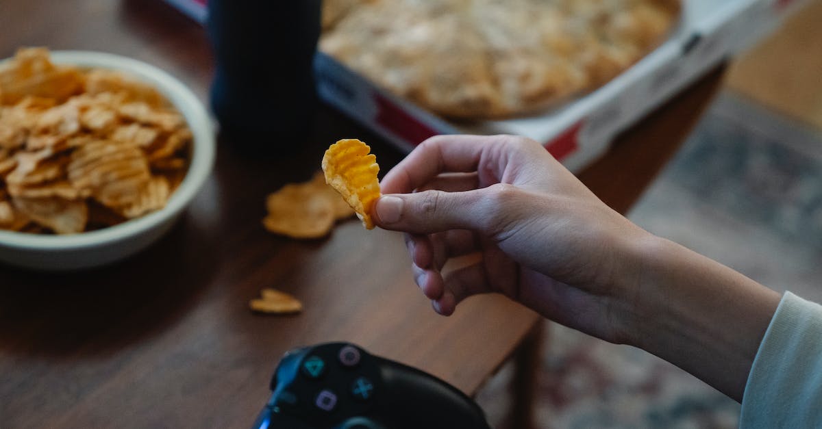 Using second hand Skylander games - Crop gamer with potato chip and joystick in room