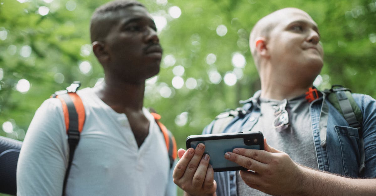 Using the map after update [duplicate] - Low angle of multiethnic young male tourists checking route on cellphone while having adventure in woods