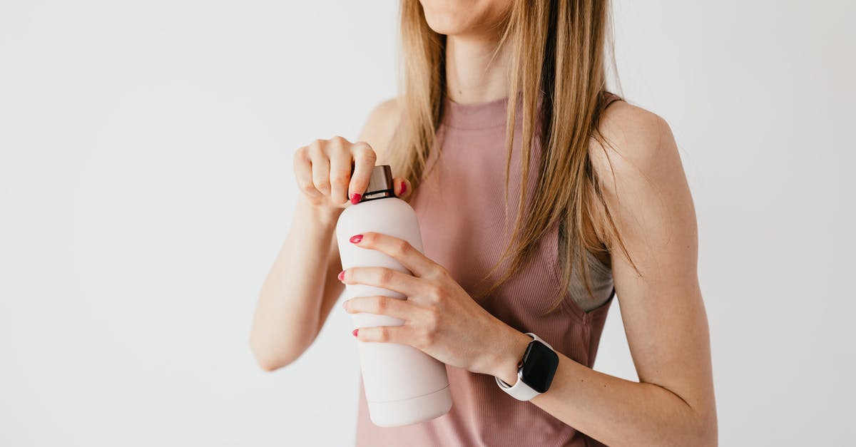 Vessels escaping host bodies over time - Crop faceless young female in casual outfit wearing smart watch opening cosmetic bottle while standing against white background Vessels escaping host bodies over time - Crop faceless young female in casual outfit wearing smart watch opening cosmetic bottle while standing against white background