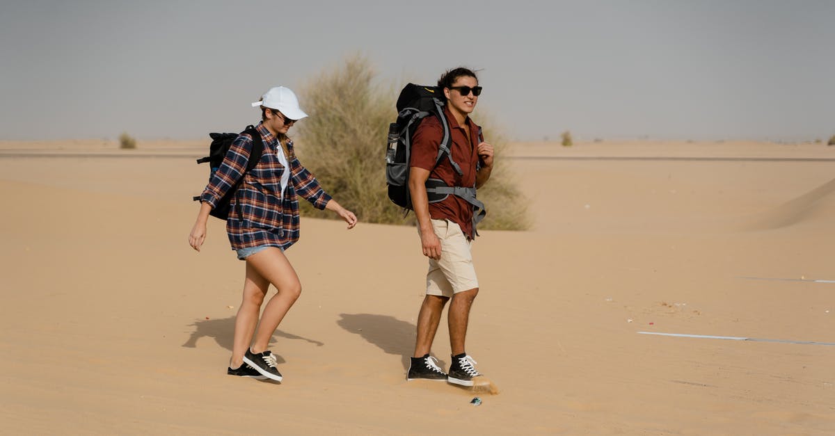Wasteland exploration - A Couple of Backpackers Walking on a Desert Wasteland exploration - A Couple of Backpackers Walking on a Desert