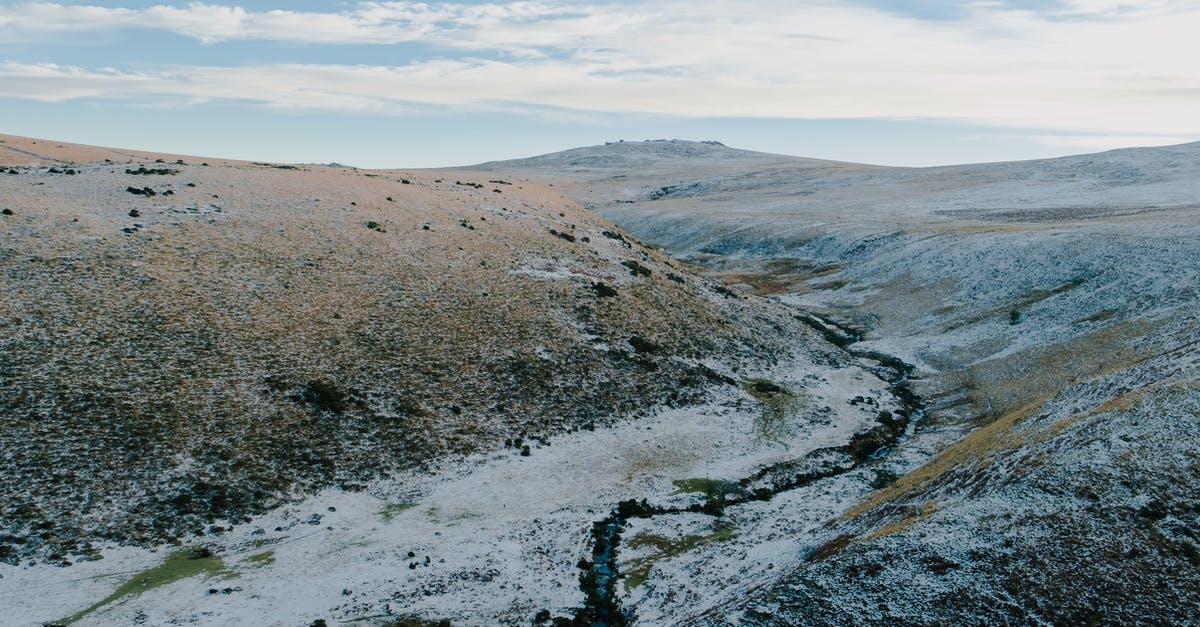 Water on top of slowly receding magma and obsidian-based floor formations - flow control? - Picturesque scenery of curving brook flowing between high hills covered with snow in nature Water on top of slowly receding magma and obsidian-based floor formations - flow control? - Picturesque scenery of curving brook flowing between high hills covered with snow in nature