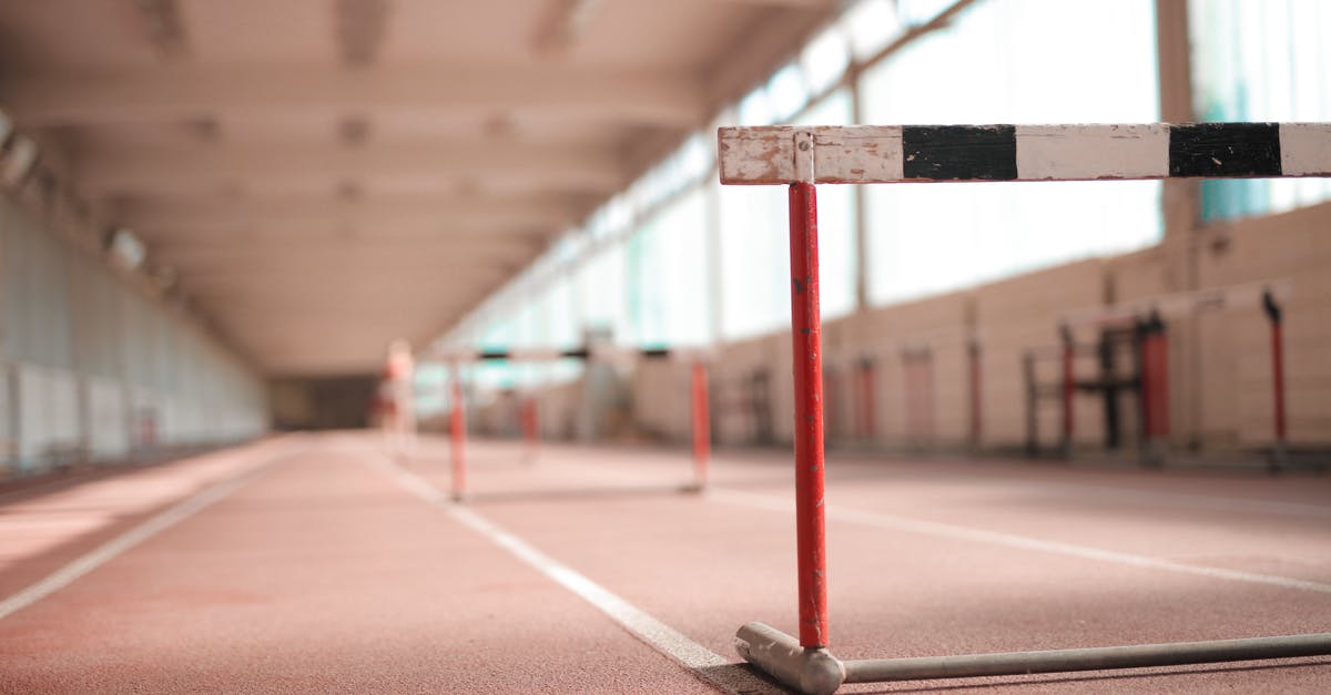 Way of white circlet - Hurdle painted in white black and red colors placed on empty rubber running track in soft focus
