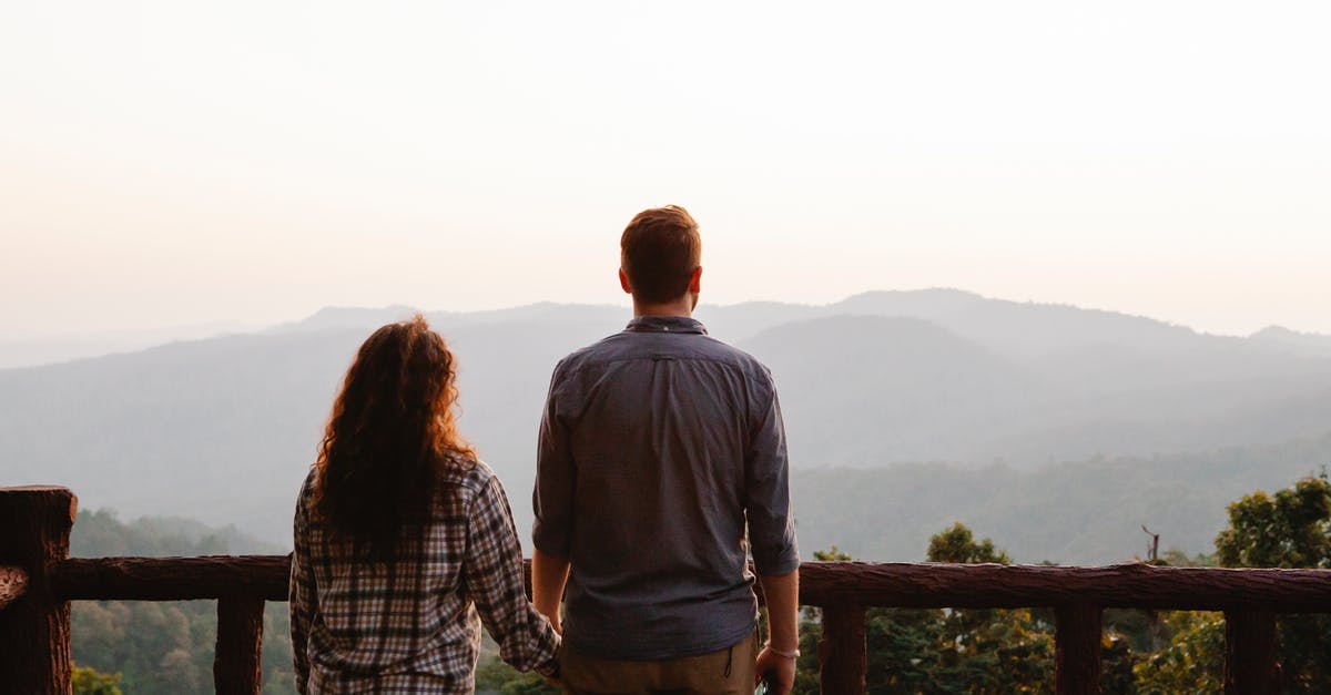 Weapon-Range: How does it affect gameplay? - Back view of anonymous young couple in casual clothes holding hands while recreating on terrace and admiring amazing mountain ridge against sunset sky
