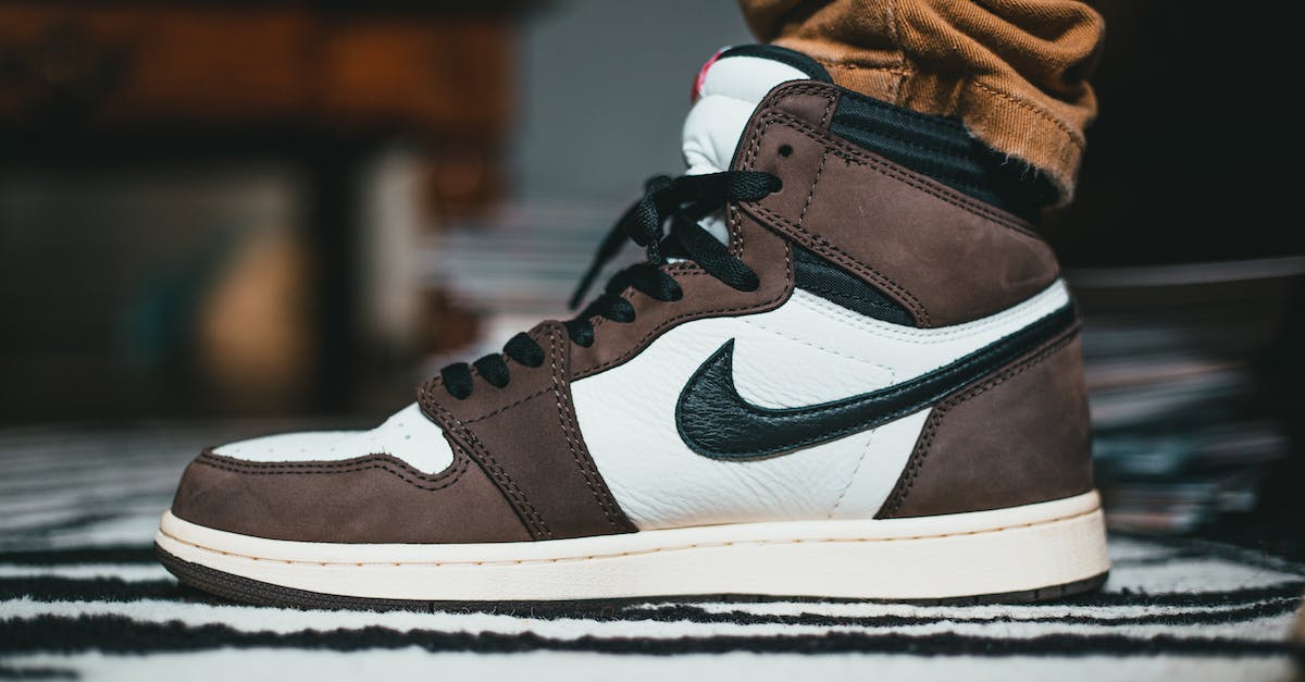 Weapons in brand new world reforging on their own? - Crop leg of person wearing trendy sneakers made of white leather and brown suede and black shoelace and brand logotype Weapons in brand new world reforging on their own? - Crop leg of person wearing trendy sneakers made of white leather and brown suede and black shoelace and brand logotype