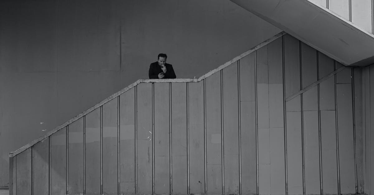 What's considered a step in Pokemon? [duplicate] - Black and white emotionless adult male in black jacket smoking cigarette and standing on outdoor building stairway
