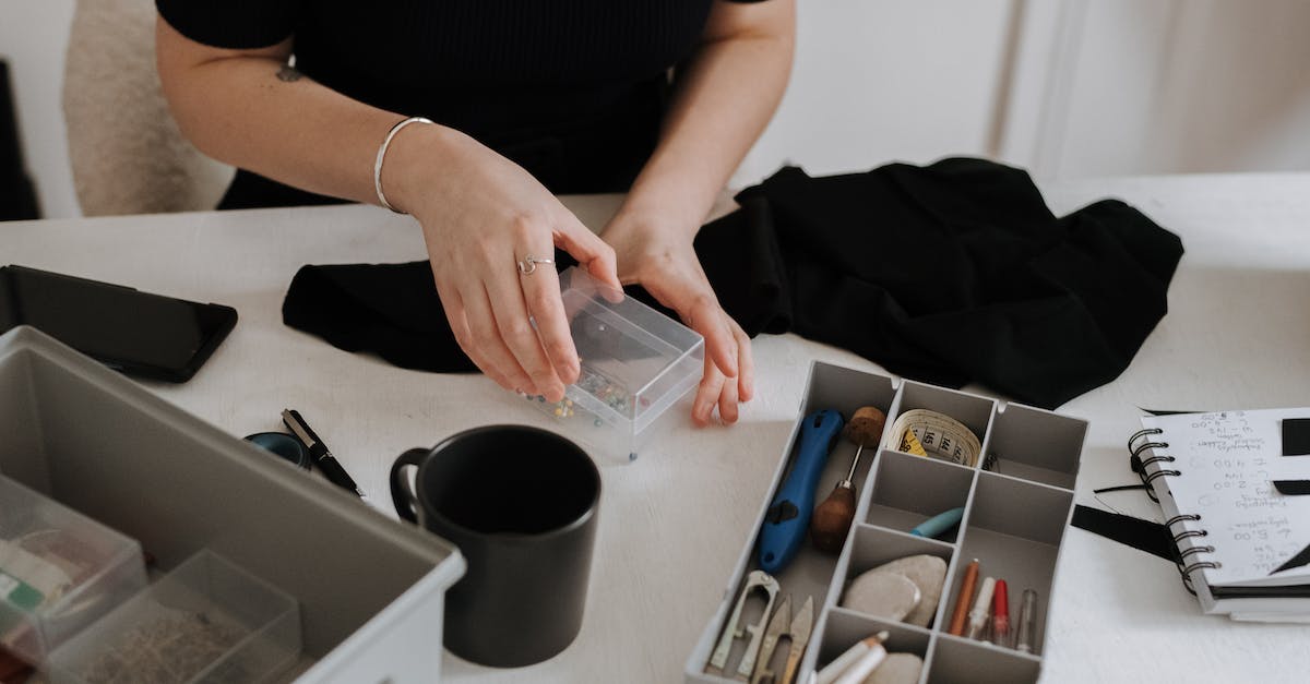 What's the Atelier Rorona Plus Premium Box? - Unrecognizable female dressmaker with box of pins standing at table with containers full of sewing supplies while working in light workshop