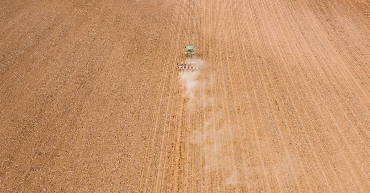 What's the minimum height for the spawning area of a mob farm? - Contemporary tractor leaving long traces and smoke while plowing brown plantation in daylight