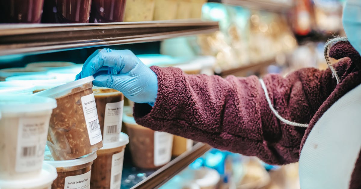 What's the most efficient food source to keep my hunger and thirst levels in check in Survival? - Crop anonymous female customer in protective mask reading label on frozen food in plastic container in grocery store