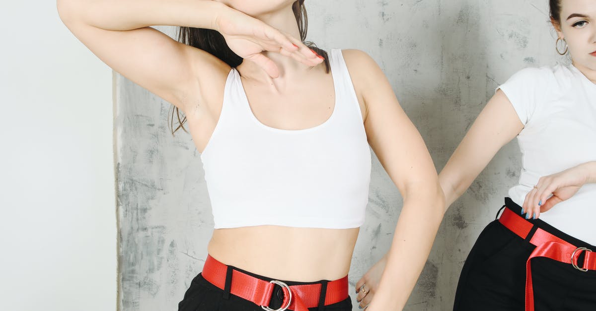 What's the non-poking action that makes Partner Eevee sad? - Crop young female dancers in same clothes with red belt and in black pants making dancing movements near gray wall