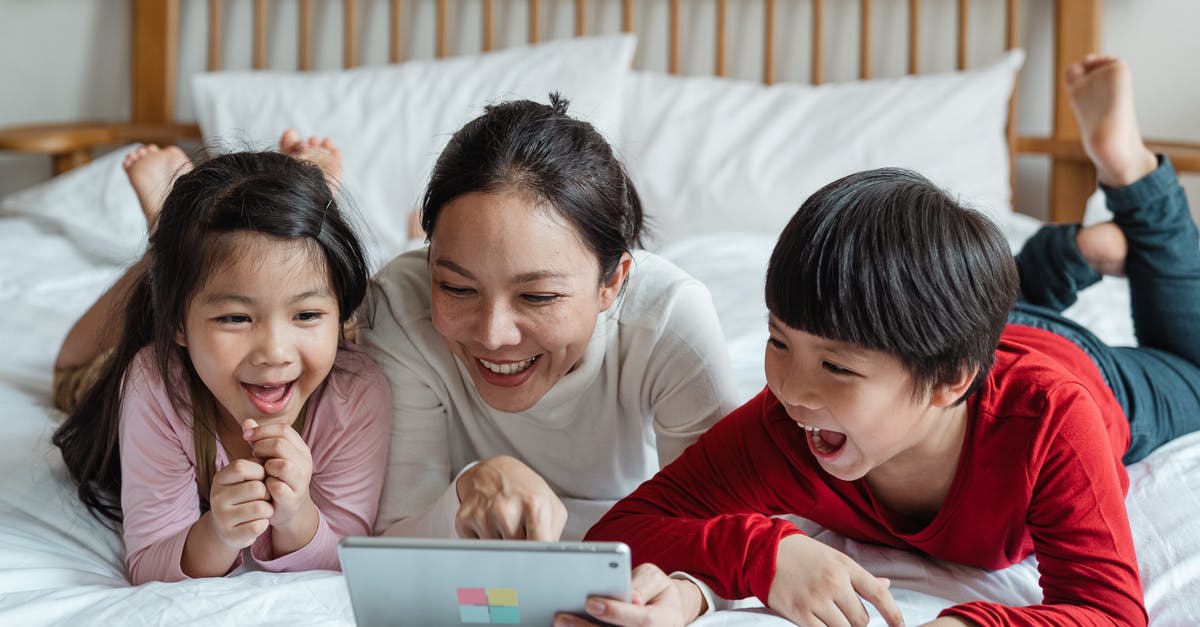 What's the point of having more engineers? - Full body happy Asian mother pointing at screen tablet showing interesting information to cheerful kids while lying on cozy bed in light room What's the point of having more engineers? - Full body happy Asian mother pointing at screen tablet showing interesting information to cheerful kids while lying on cozy bed in light room