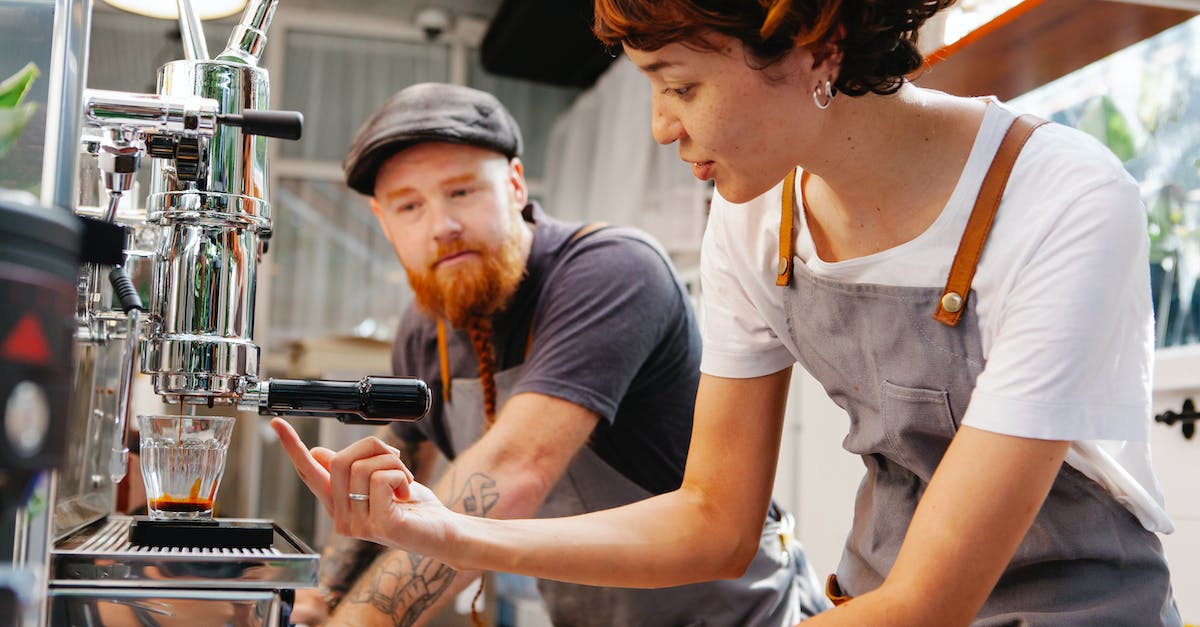 What's the point of the glass cases? - Crop baristas talking while brewing coffee in professional machine What's the point of the glass cases? - Crop baristas talking while brewing coffee in professional machine