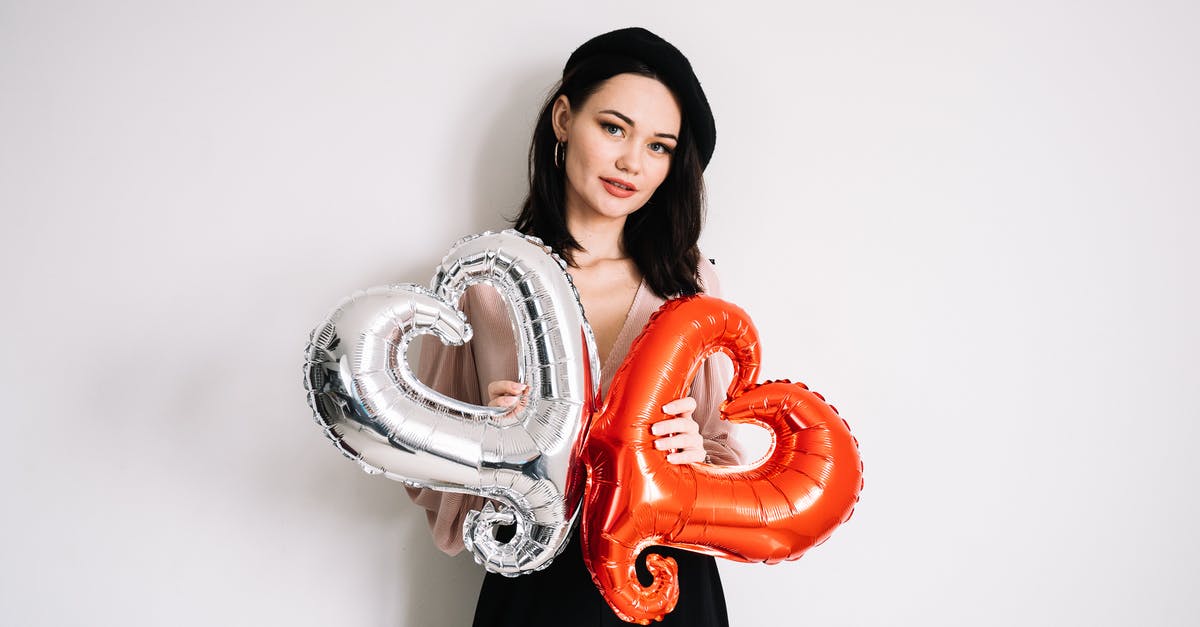 What's the purpose of this holey wall? - Woman in Black and White Clothes Holding Heart Shaped Balloon
