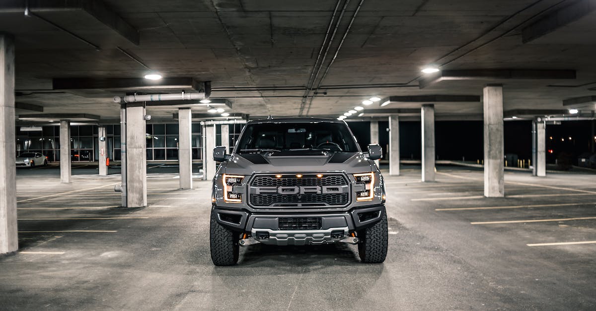 What affects the driving of the truck directly? - Modern gray pickup with glowing headlights parked on asphalt in underground parking lot with columns in evening time in city