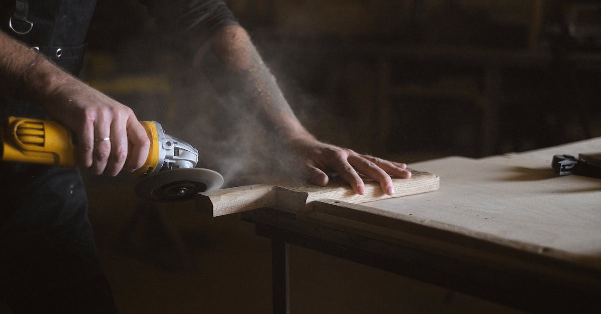 What are all the Beacon Special Effects? - Unrecognizable male master using electric angle grinder to polish lumber plank while standing at table in professional joinery during work