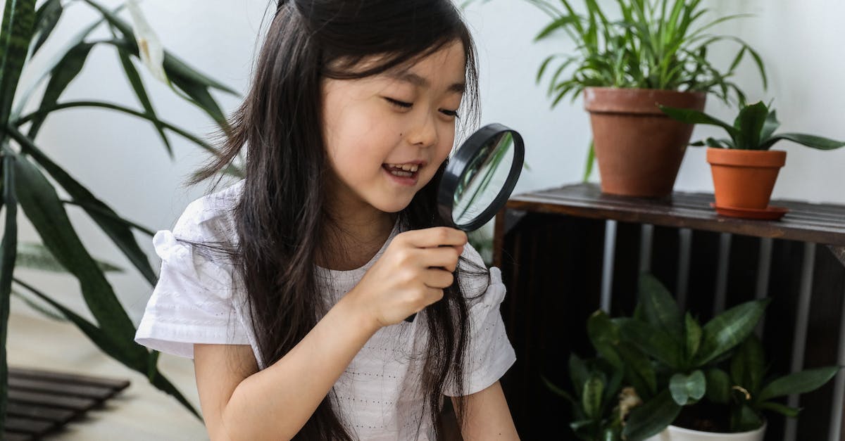 What are home grown players? - Little happy cute Asian girl looking at magnifier