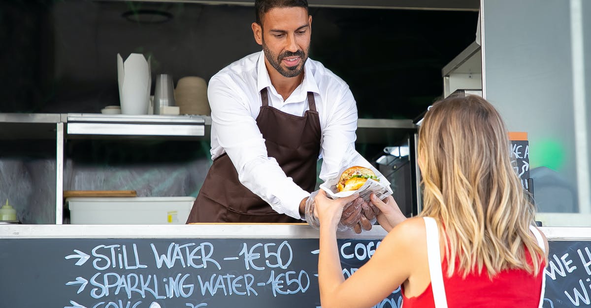 What are the abilities you can give your custom character? - Positive ethnic cook in apron standing at counter in food truck and giving delicious hamburger to anonymous woman customer in daytime