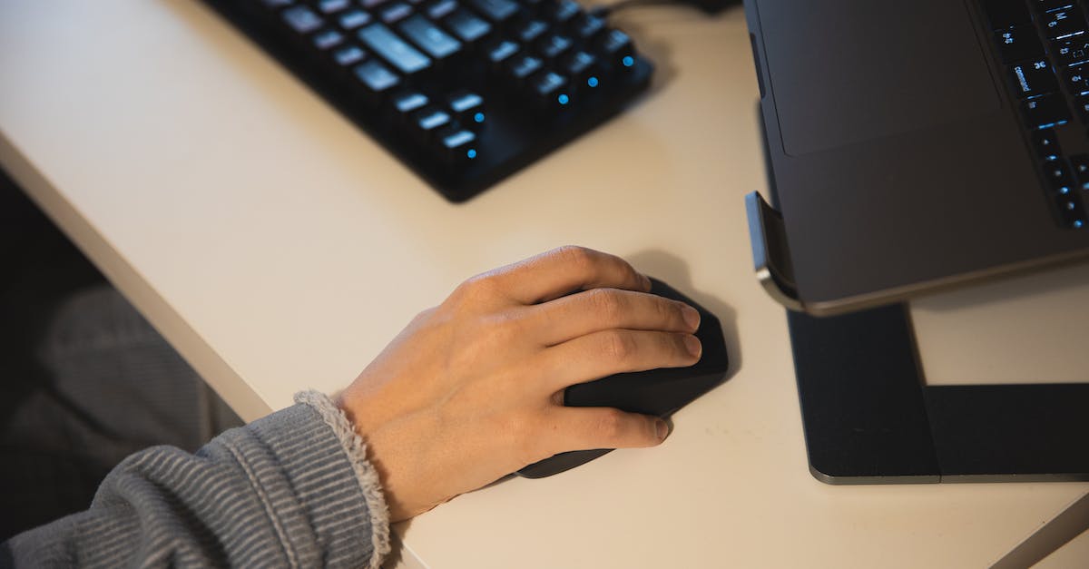 What are the advantages of binding a secondary to your left mouse button - Faceless person working on computer using mouse and keyboard and having laptop on cradle