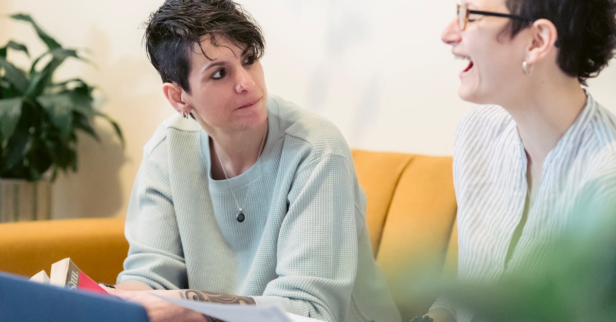 What are the best job combinations? - Crop cheerful young woman with short dark hair laughing with closed eyes while working remotely on laptop at home sitting on sofa with female friend