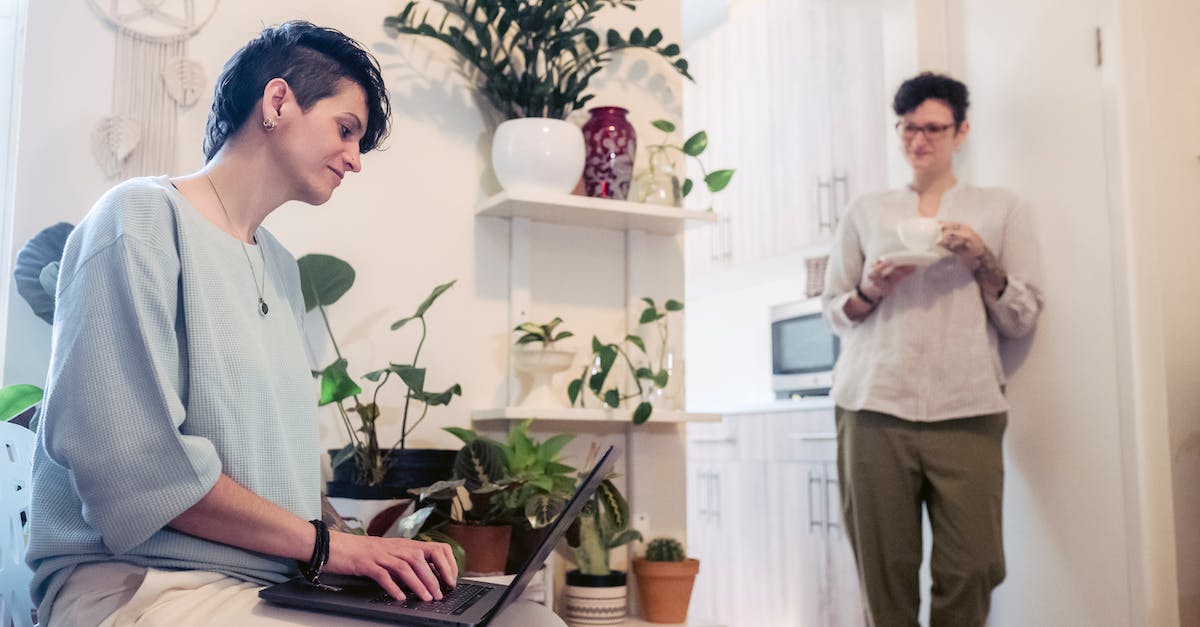 What are the best job combinations? - Young woman with short hair standing near wall with cup of coffee and communicating with female friend working remotely on laptop at home