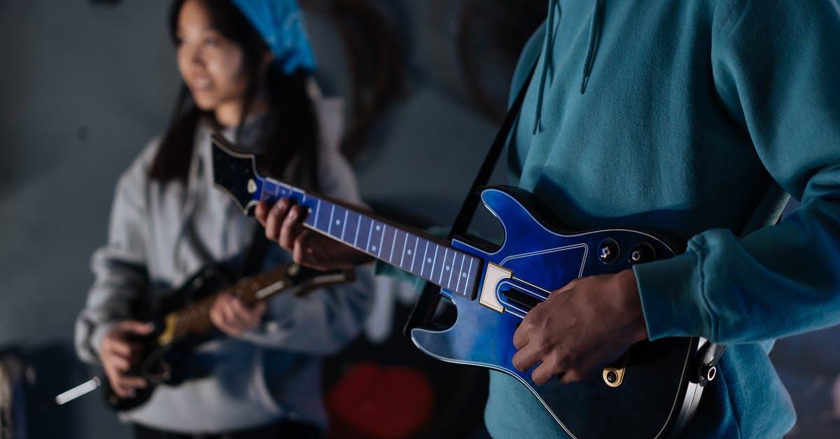 What are the differences between the following versions of Guitar Hero? - Person Playing a Blue Guitar Hero Live