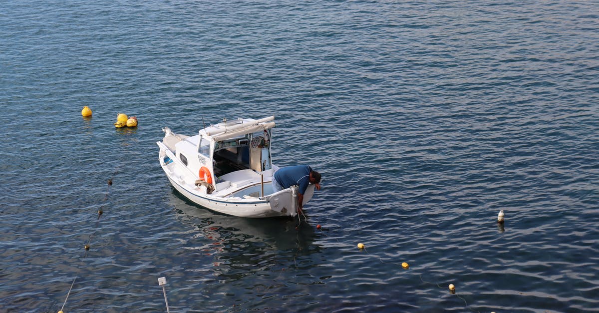 What are the floating dots? - Man in Blue Shirt on White Fishing Boat