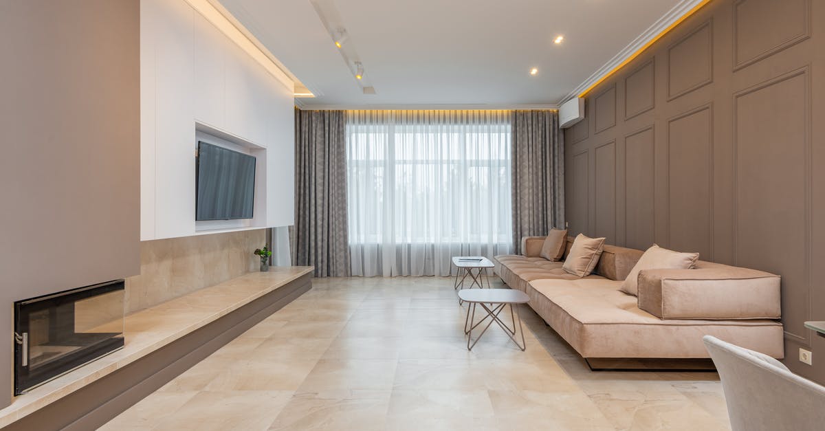 What are the huge flat Monoliths good for? - Comfortable huge couch with wide seat decorated with cushions placed along brown wall in stylish spacious room with TV set hanging on wall and coffee tables near