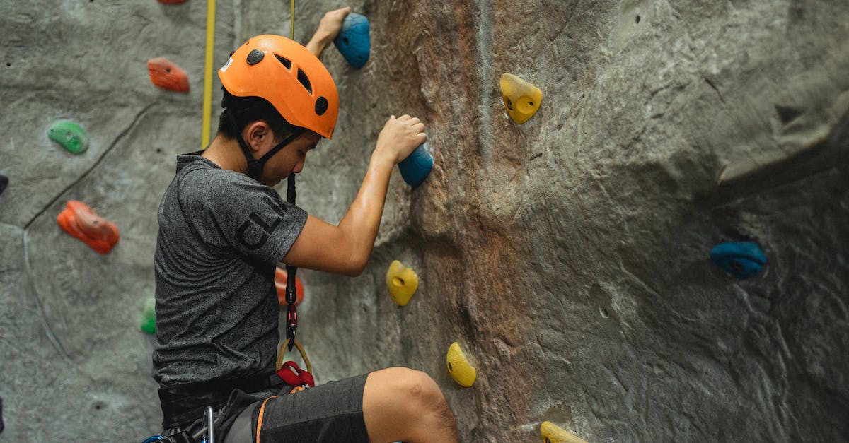 What are the missable equipment/items in Bravely Default? - Side view of crop young Asian man in orange helmet and belay ascending on climbing wall during training in bouldering center