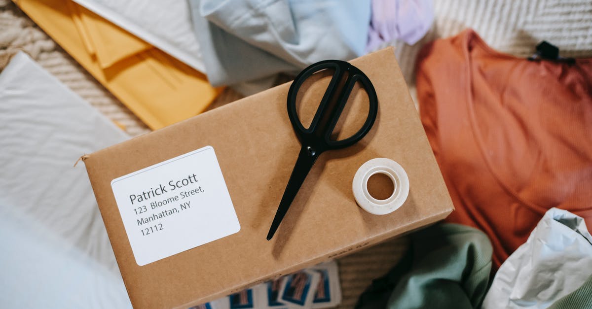 What are the names of the Postal 2 Levels? - Top view of tape with scissors on carton box with exact address and name among clothes What are the names of the Postal 2 Levels? - Top view of tape with scissors on carton box with exact address and name among clothes