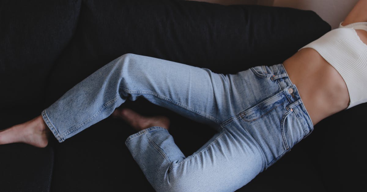 What are the repercussions of letting Skinny Malone live? - Crop anonymous barefoot female wearing stylish blue jeans and white crop top lying on black comfortable sofa against white wall