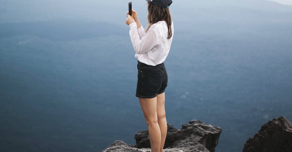 What are the situations where taking Smite/Teleport top is appropriate? [duplicate] - Unrecognizable woman on cliff taking photo of landscape on smartphone