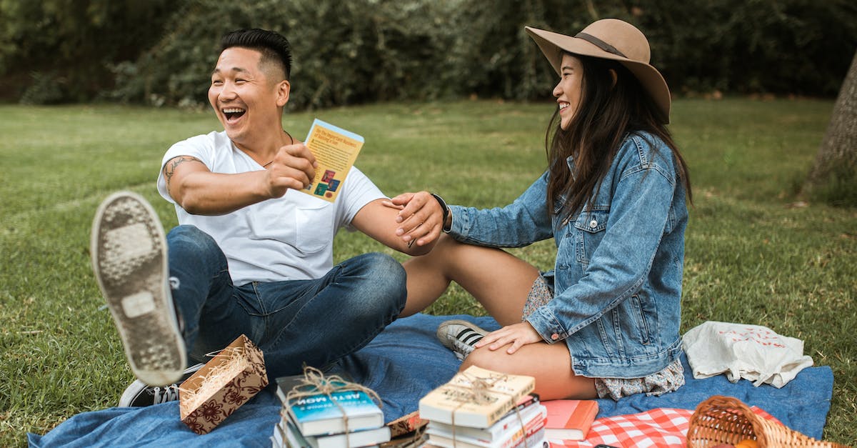 What Badges don't you get in Picnic Difficulty? - Man in White T-Shirt Holding a Book and Sitting Beside Woman in Hat