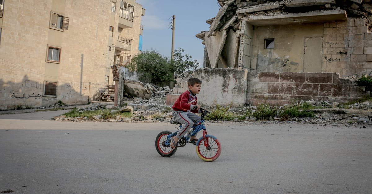 What can get destroyed in your settlements? - Full body side view of boy in casual clothing riding on bicycle along old ruined construction in daytime What can get destroyed in your settlements? - Full body side view of boy in casual clothing riding on bicycle along old ruined construction in daytime