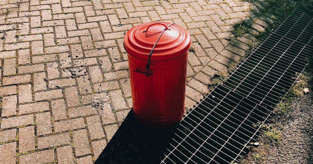 What can I do with a Sunlight Threshcone? - High angle of red metal trash can placed on pavement near sewer grates in city street in sunny summer day