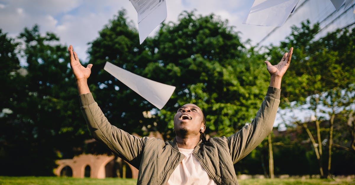 What champions have done the biggest heal? - Cheerful young African American male student in casual clothes throwing college papers up in air while having fun in green park after end of exams