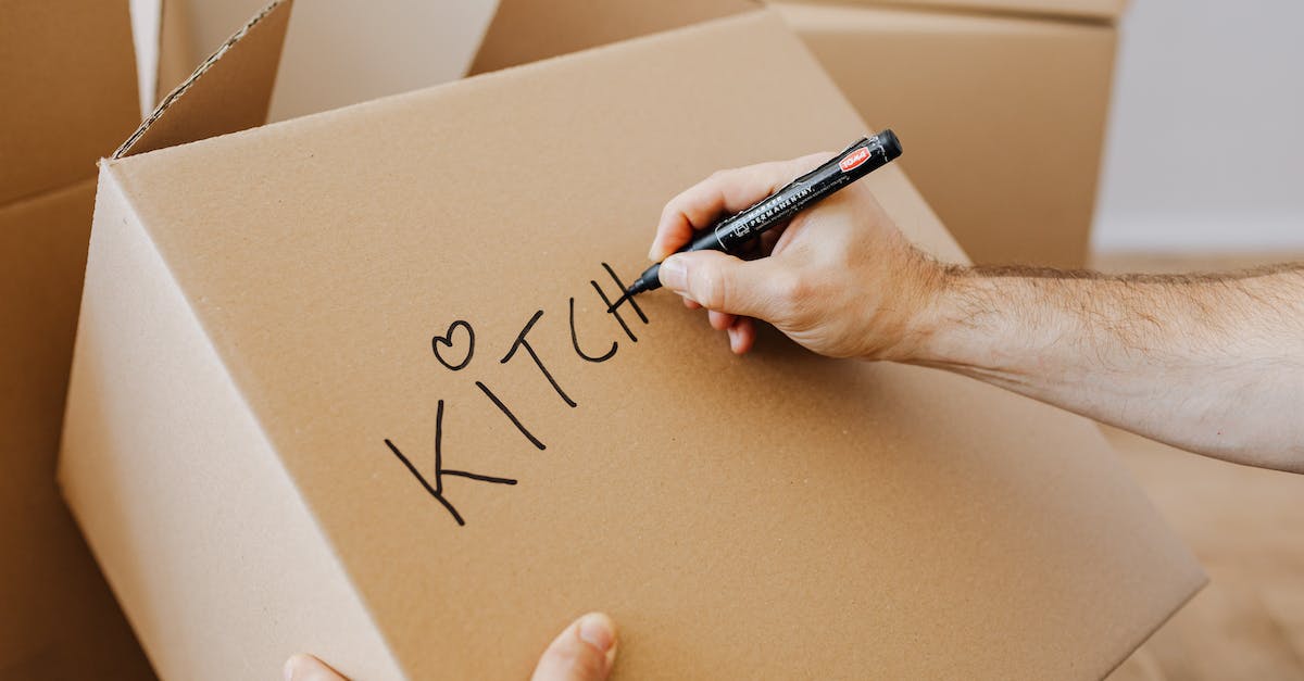 What changes during the night-time? - From above of unrecognizable adult male writing with black marker on cardboard containers while packing staff and preparing for relocation in new home