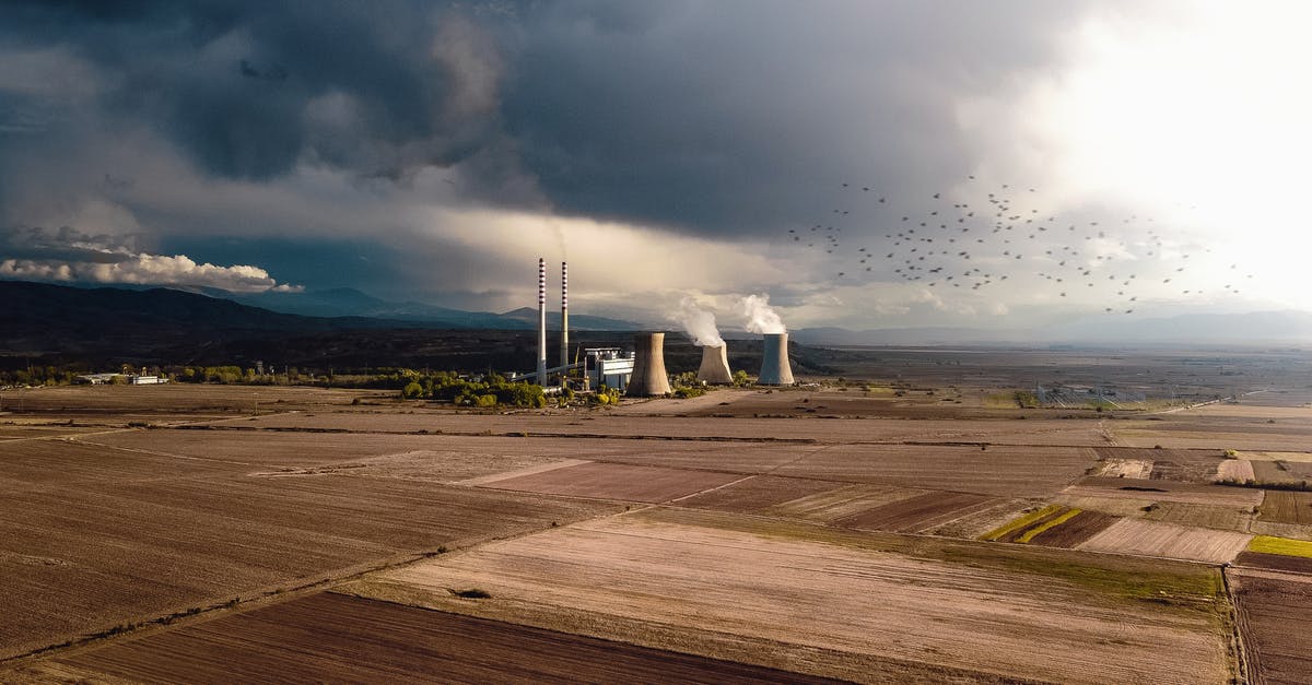 What changes when I build a nuclear weapon? - Aerial view of empty fields near atomic power station generating energy and polluting atmosphere
