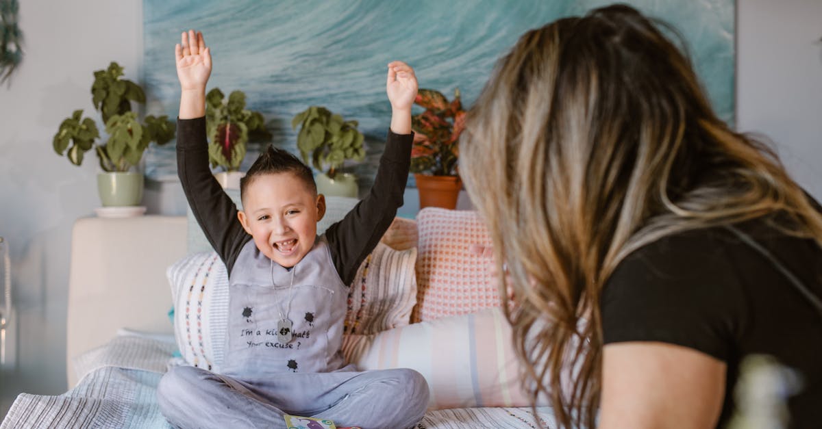 What code do I have to input at the end of You Have to Win the Game? - Happy boy raising arms after winning card game sitting on bed with unrecognizable mother