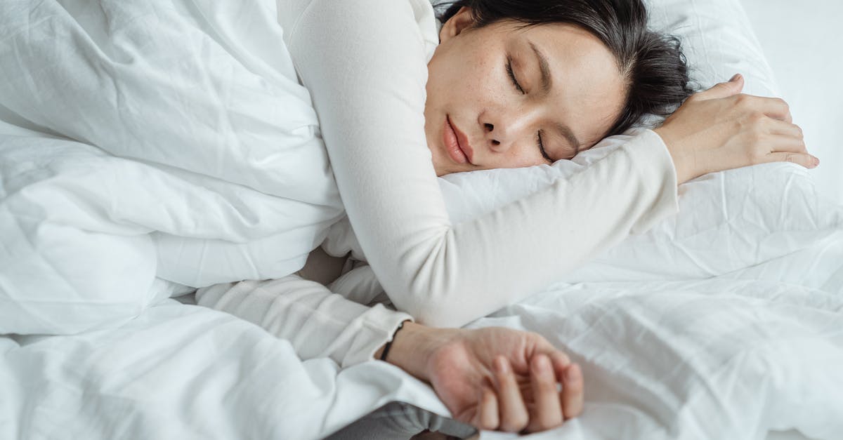 What command can let a player sleep in the morning? - Calm Asian female wearing white pajama sleeping in comfortable bed with white sheets near modern mobile phone in morning