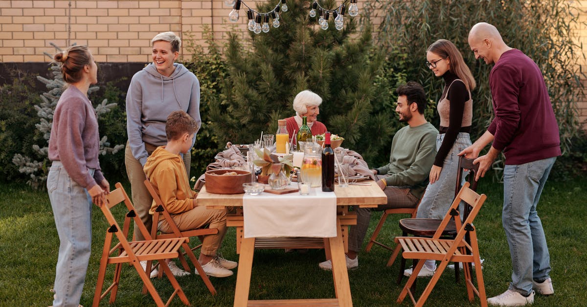 What conditions cause a party to naturally occur? - Happy family members talking and sitting down to eat tasty food at big wooden table in backyard in daytime