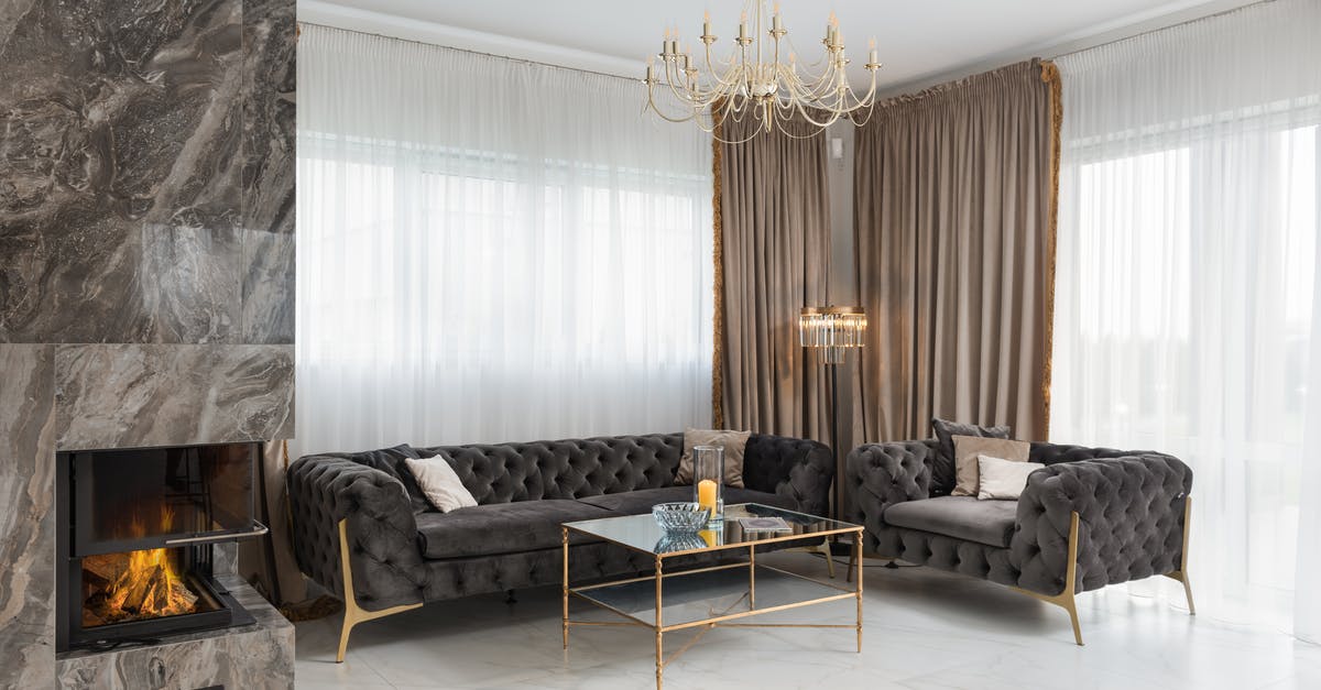 What contributes to extinguishing room fires faster? - Interior of modern apartment with comfortable seats with side table placed at windows near burning fireplace in spacious room with chandelier What contributes to extinguishing room fires faster? - Interior of modern apartment with comfortable seats with side table placed at windows near burning fireplace in spacious room with chandelier