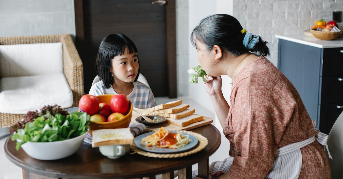What could help give the 'wobbly' status in Pokemon Rumble world? - Ethnic mom giving salad leaf to girl while eating together at table in lunch time
