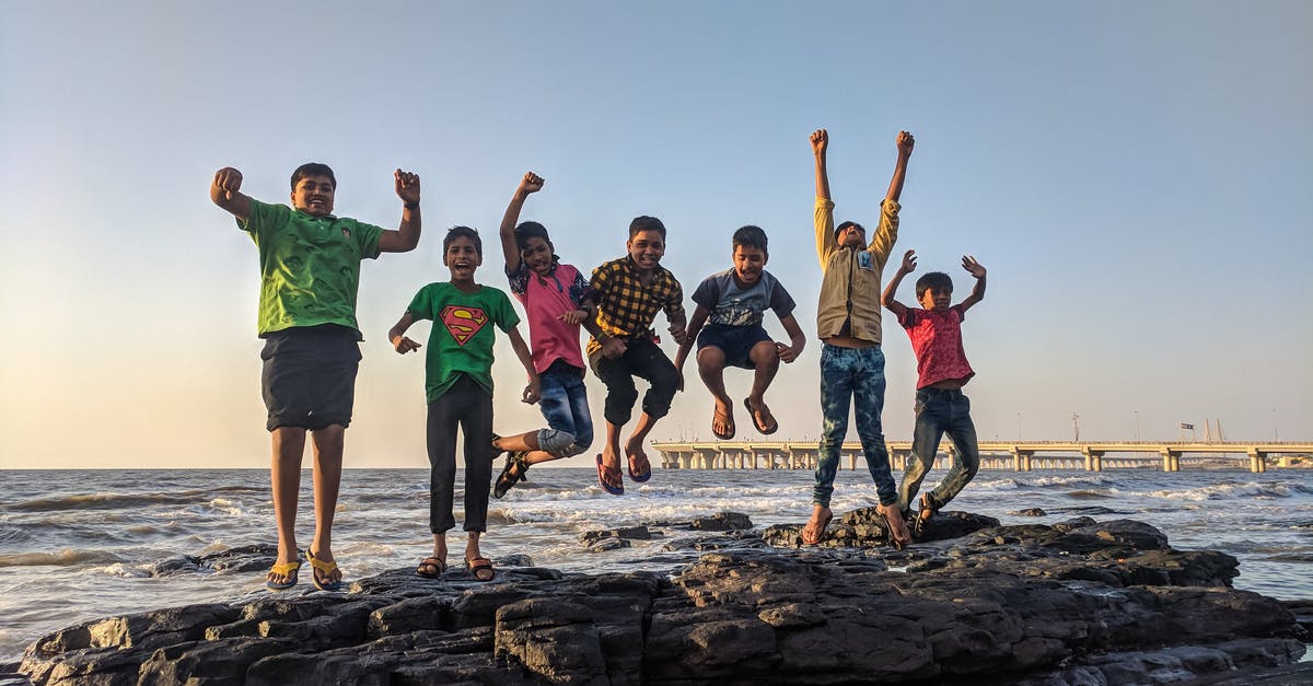 What counts as a day for water purifiers? - Boy Wearing Green Crew-neck Shirt Jumping from Black Stone on Seashore