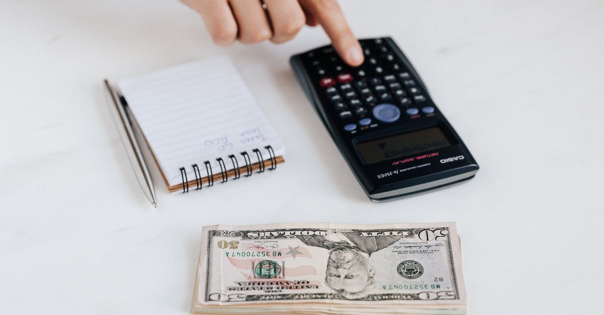 What currency is used in all of the Pokemon games? - Top view of crop faceless economist touching calculator button while counting income near heap of paper bills and small notebook with pen
