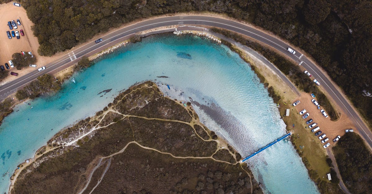 What determines the direction a river takes in Alpha Centauri? - Drone view of curvy asphalt road with many automobiles and narrow blue clean river What determines the direction a river takes in Alpha Centauri? - Drone view of curvy asphalt road with many automobiles and narrow blue clean river