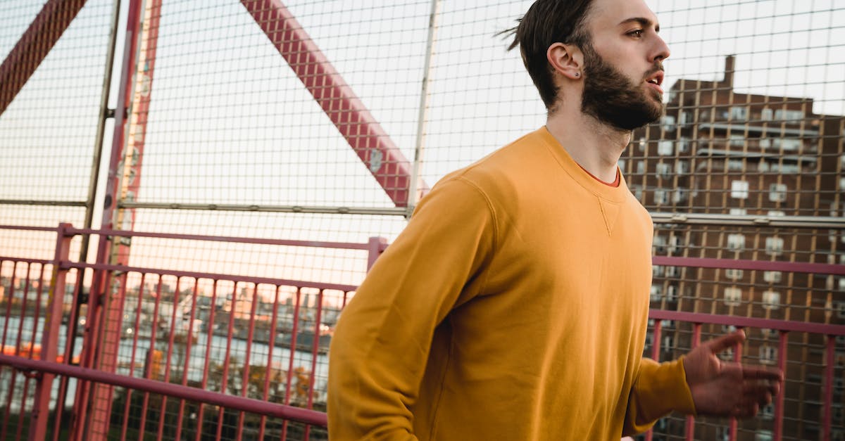 What determines where red phantoms invade (PvP)? - Side view of bearded sportsman running on pedestrian bridge along metal fence while training on street with building on background